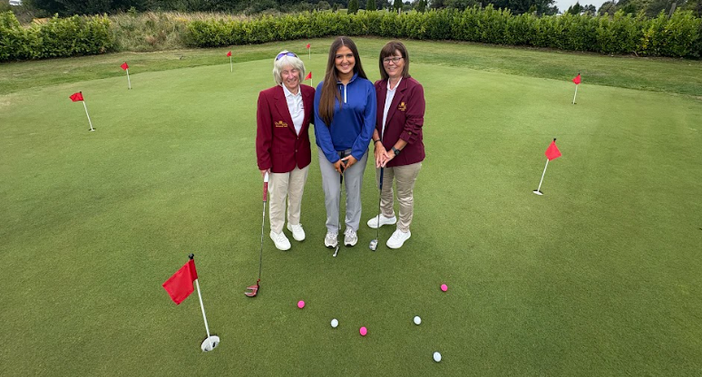 Three golfers standing on the new putting green at Cregmore Park, surrounded by practice flags.